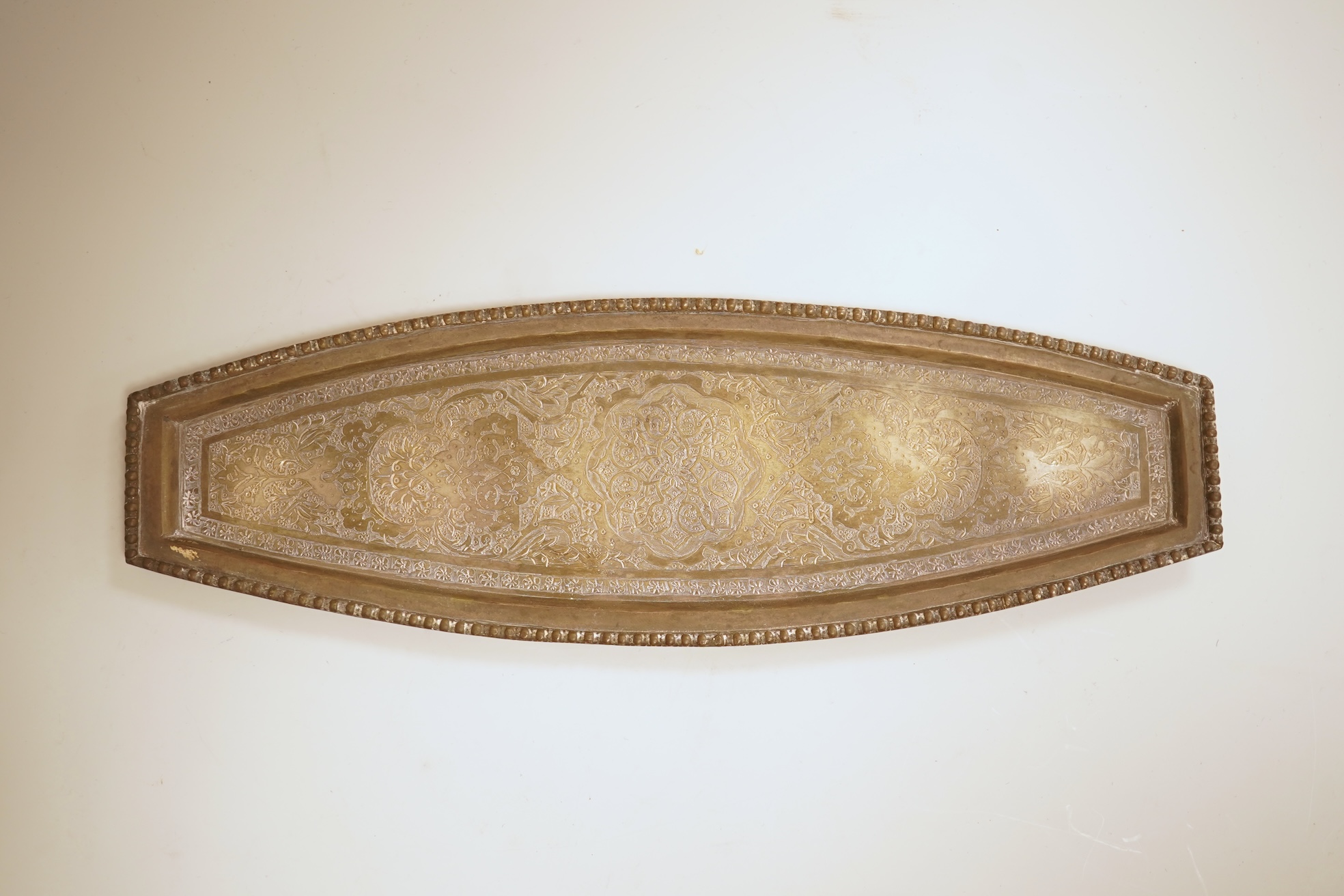 A set of six 20th century Middle Eastern white metal tots, 42mm and matching tray, 25.2cm, all engraved with geometric foliate decoration.